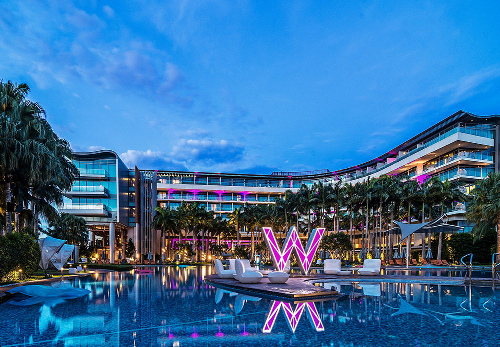 Pool side view with lit up W sculpture in pink