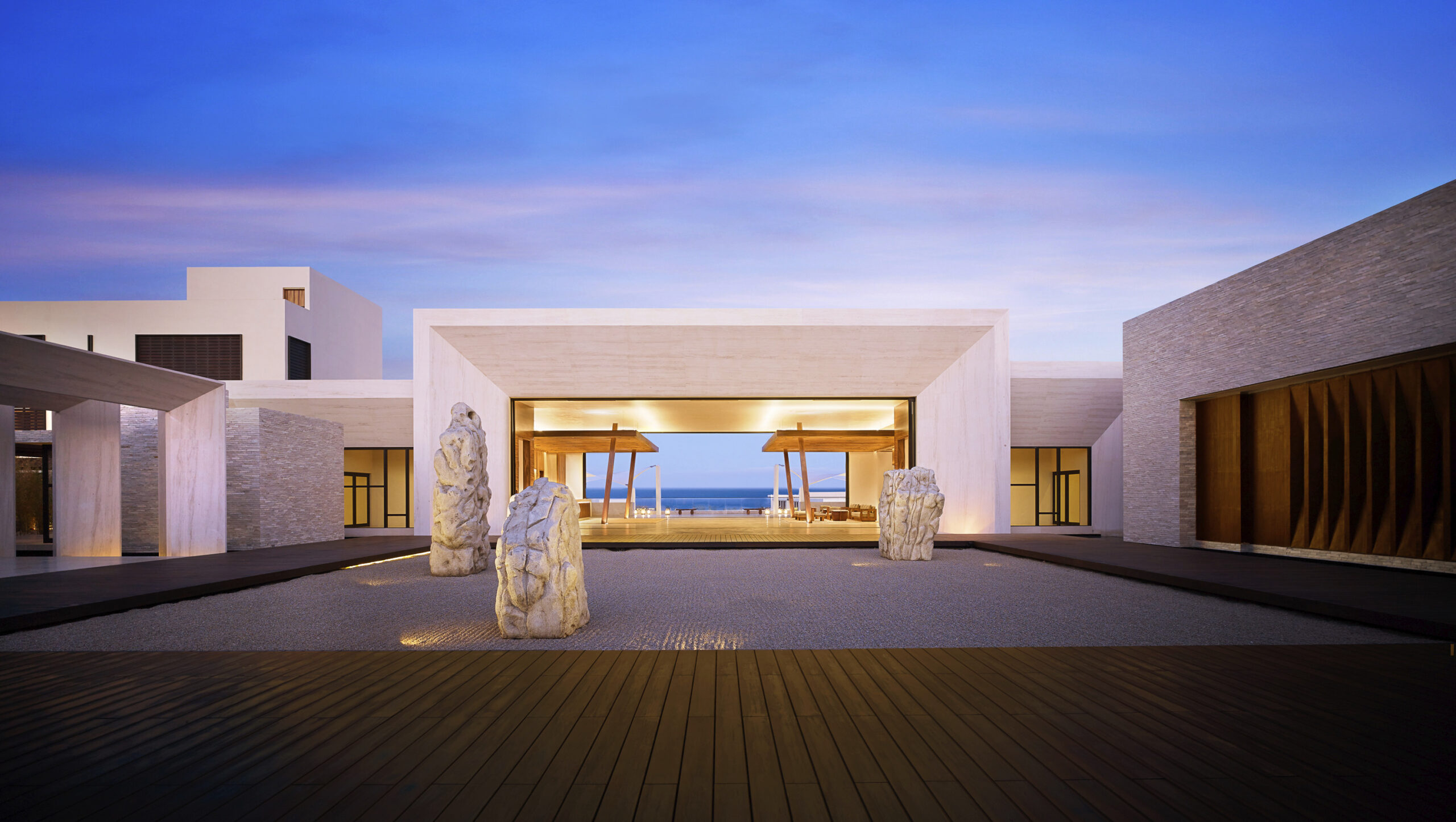 an external shot of the main entrance of Nobu hotel los cabos architecture and landscape. dramatic lighting at sunset with rock sculptures