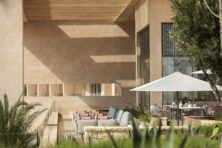 Outdoor rest area with linear pastel colored sofas and outdoor dining area with gazebo tentage