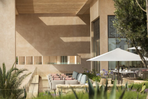 Outdoor rest area with linear pastel colored sofas and outdoor dining area with gazebo tentage