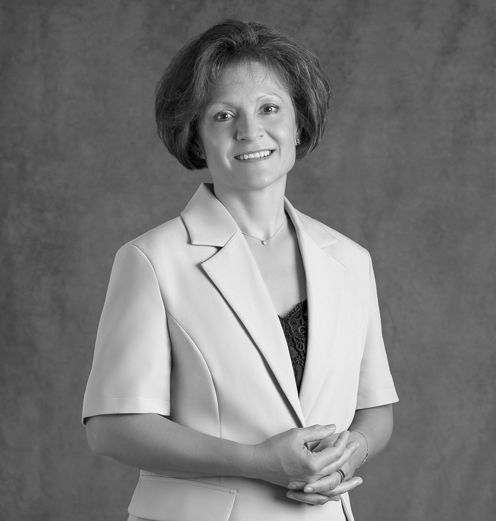 Black and white portrait of Sandra Whipp, WATG, smiling against a grey backdrop.