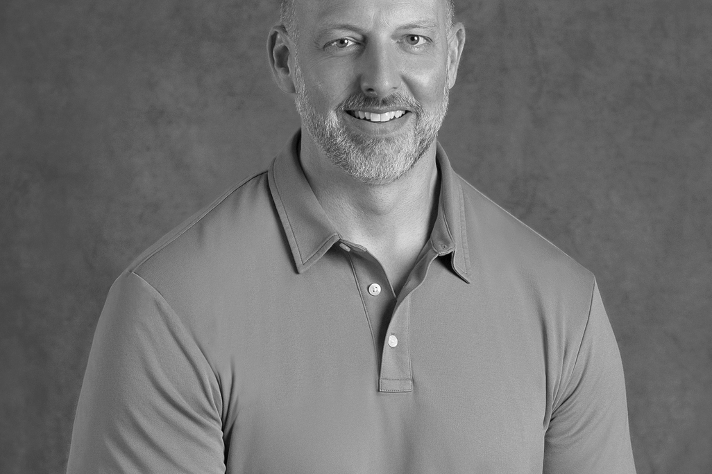 Black and white portrait of Sean Harry, WATG, smiling against a grey backdrop.