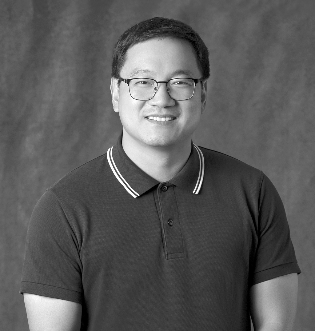 Black and white portrait of Xin Li, WATG, smiling against a grey backdrop.
