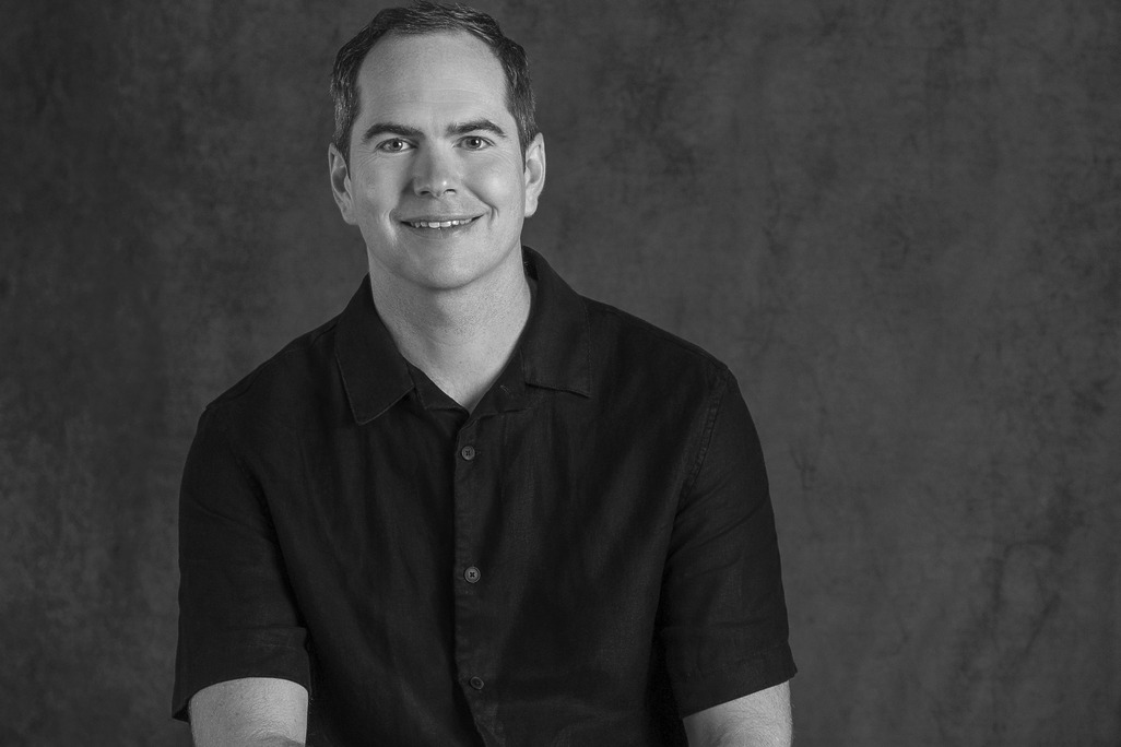Portrait of Guy Cooke, Associate Principal of Advisory Services, WATG, smiling against a grey backdrop.