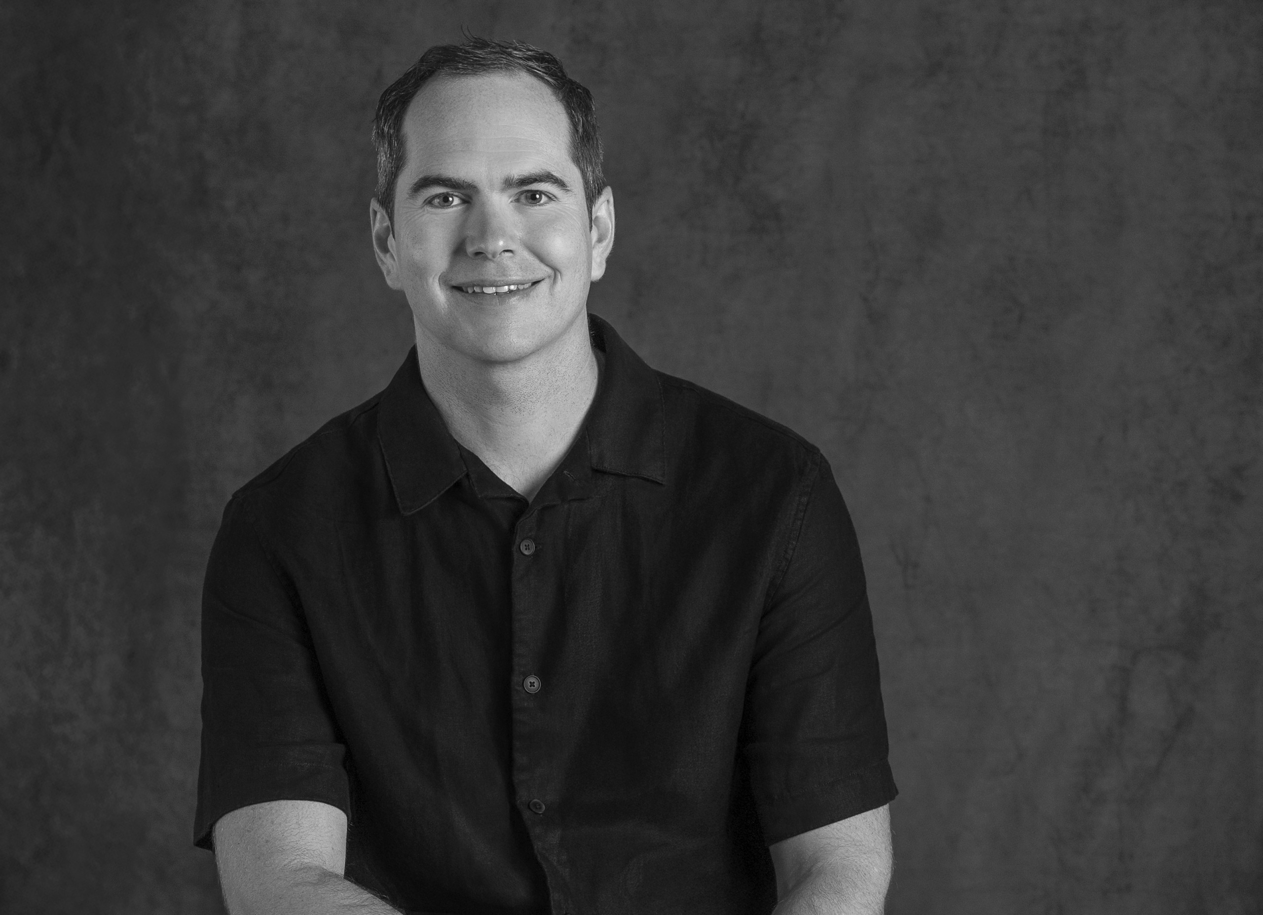 Portrait of Guy Cooke, Associate Principal of Advisory Services, WATG, smiling against a grey backdrop.