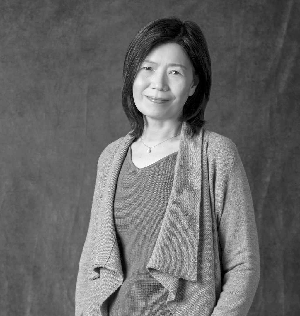 Black and white portrait of Helen Cheung, WATG, smiling against a grey backdrop.