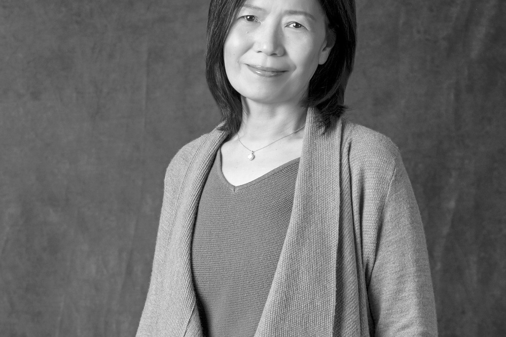 Black and white portrait of Helen Cheung, WATG, smiling against a grey backdrop.