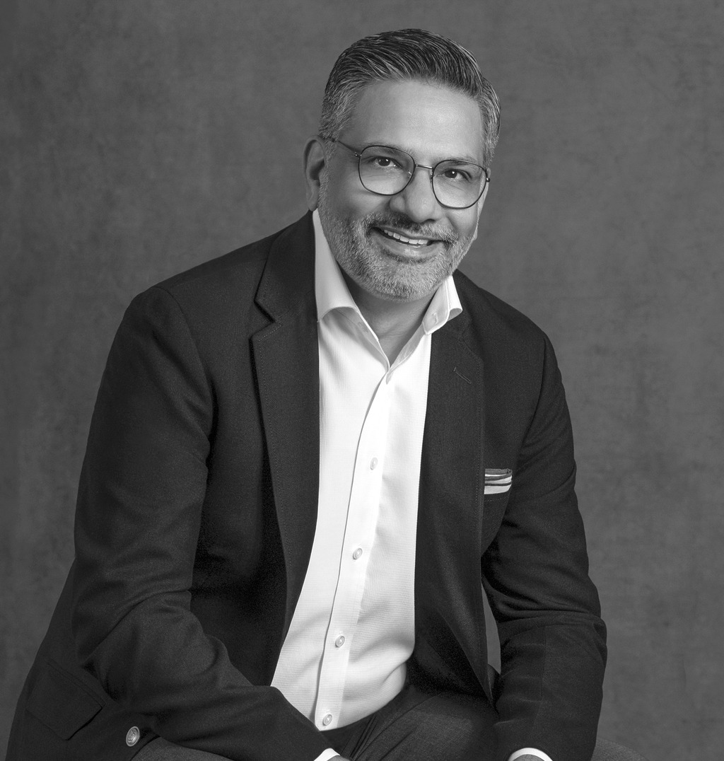 Black and white portrait of Hussain Kamal, WATG, smiling against a grey backdrop.