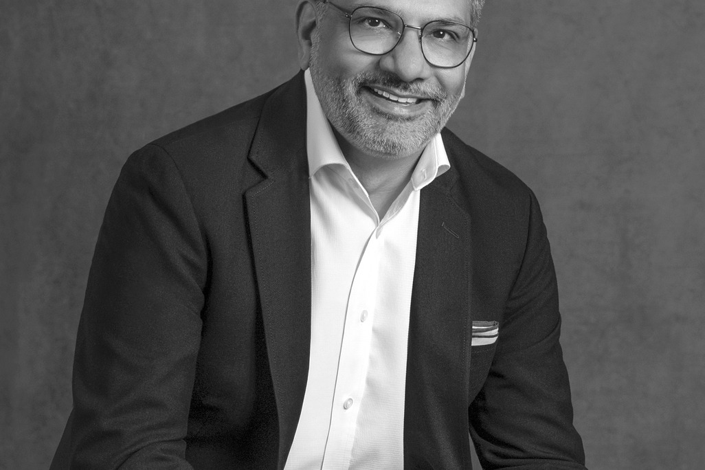 Black and white portrait of Hussain Kamal, WATG, smiling against a grey backdrop.