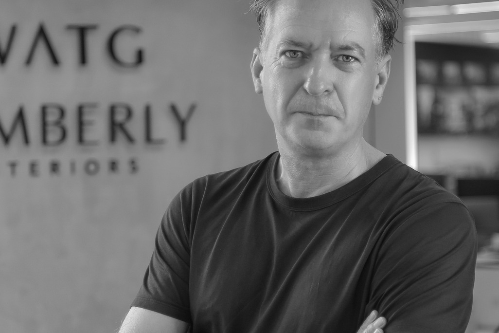 Black and white portrait of Ian Simpson, WATG, smiling against a grey backdrop.