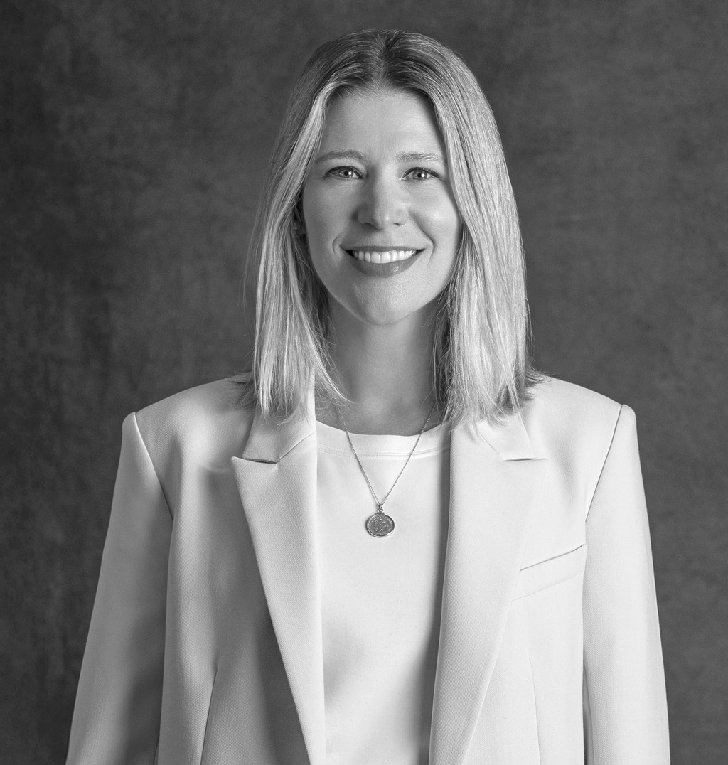 Black and white portrait of Julie Martin, WATG, smiling against a grey backdrop.