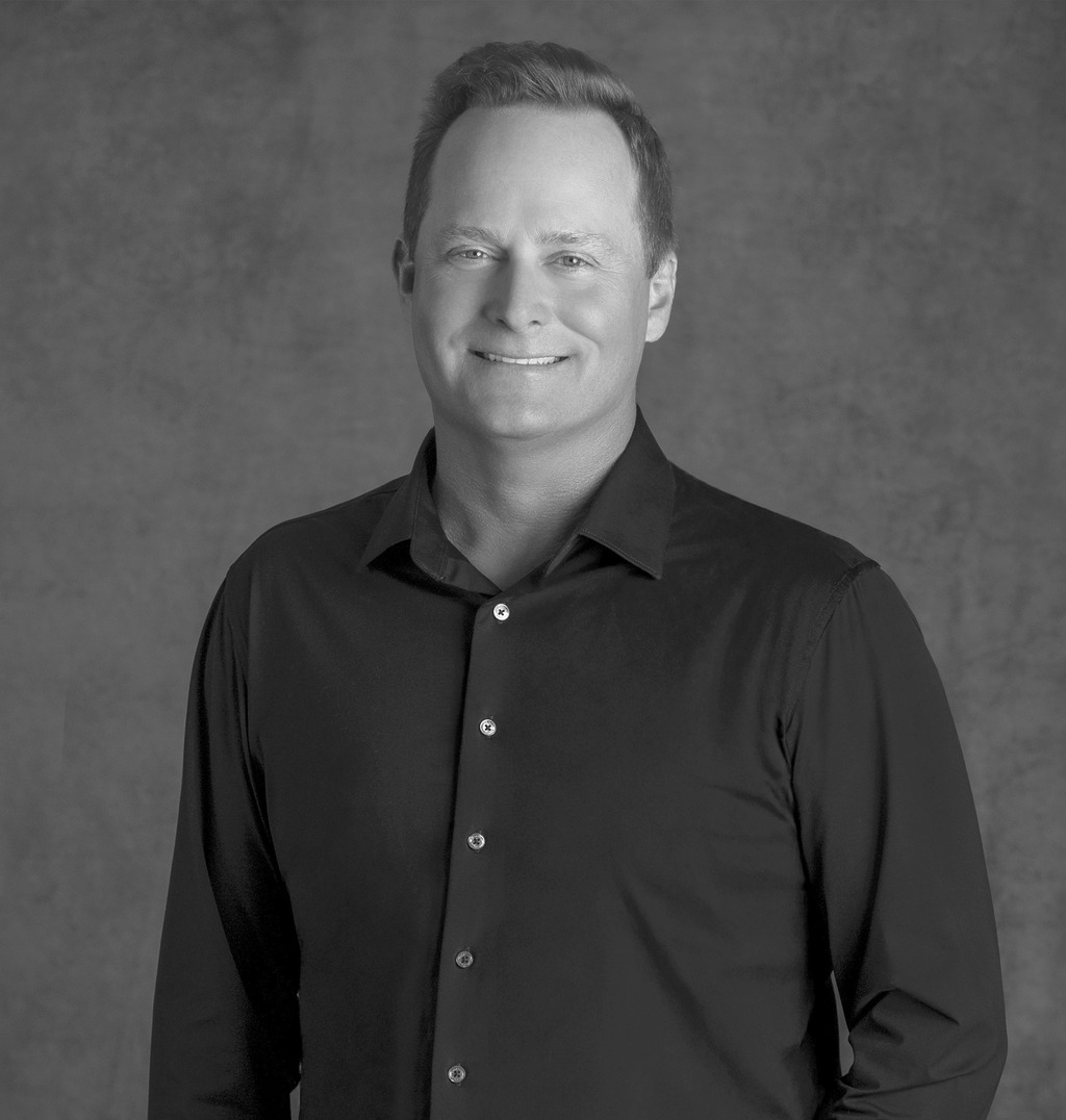Black and white portrait of Lance Walker, WATG, smiling against a grey backdrop.