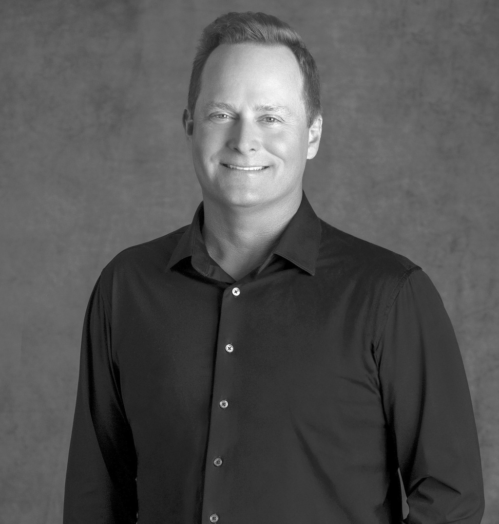 Black and white portrait of Lance Walker, WATG, smiling against a grey backdrop.
