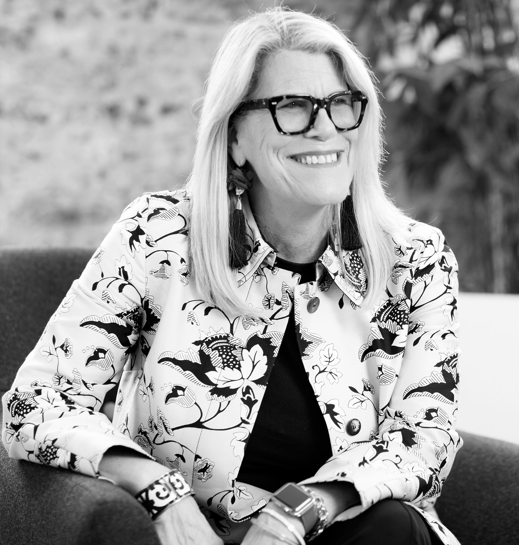 Black and white portrait of Margaret McMahon, Wimberly Interiors, smiling against a grey backdrop.