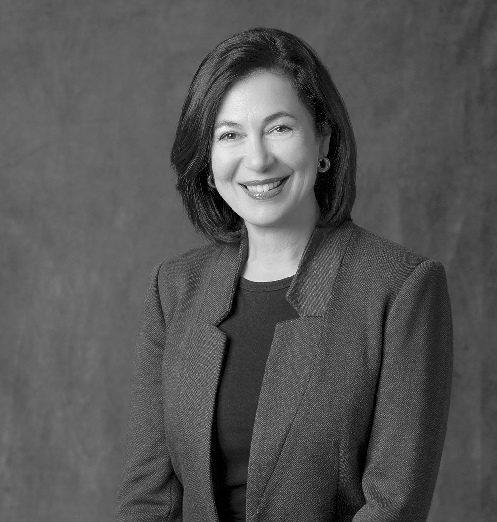 Black and white portrait of Monica Cuervo, WATG, smiling against a grey backdrop.