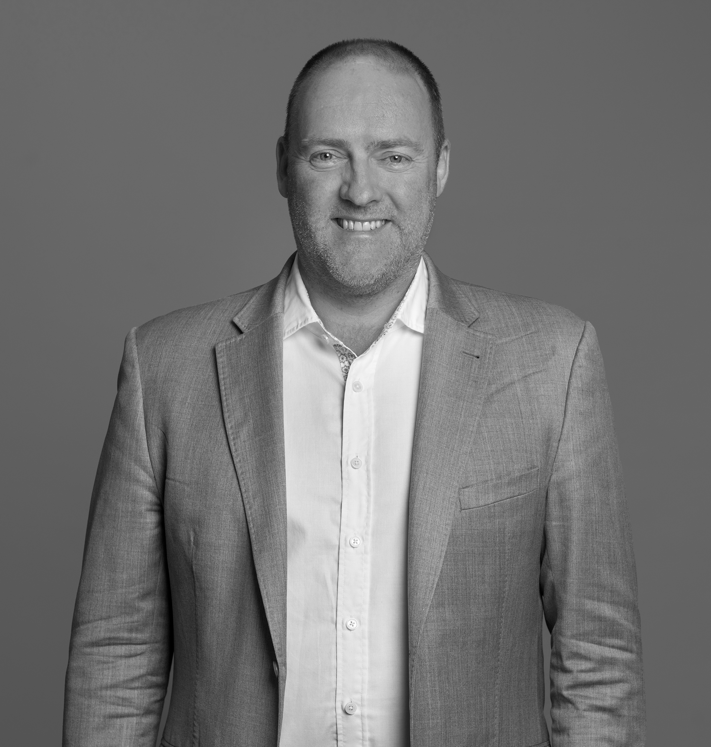 Black and white portrait of Nick Carrier, WATG, smiling against a grey backdrop.