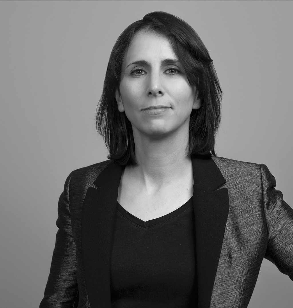 Black and white portrait of Nicole Hammond, WATG, smiling against a grey backdrop.