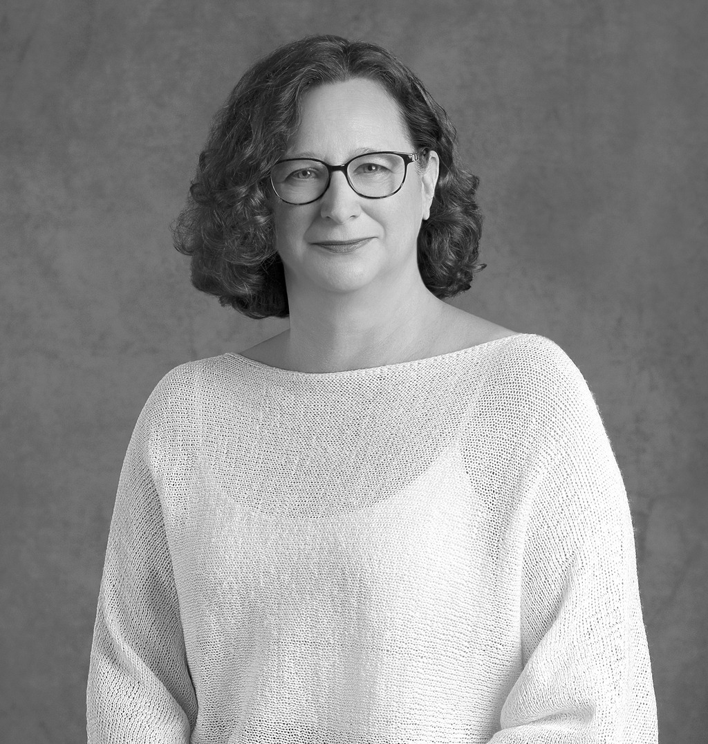 Black and white portrait of Rachel Johnson, Wimberly Interiors, smiling against a grey backdrop.