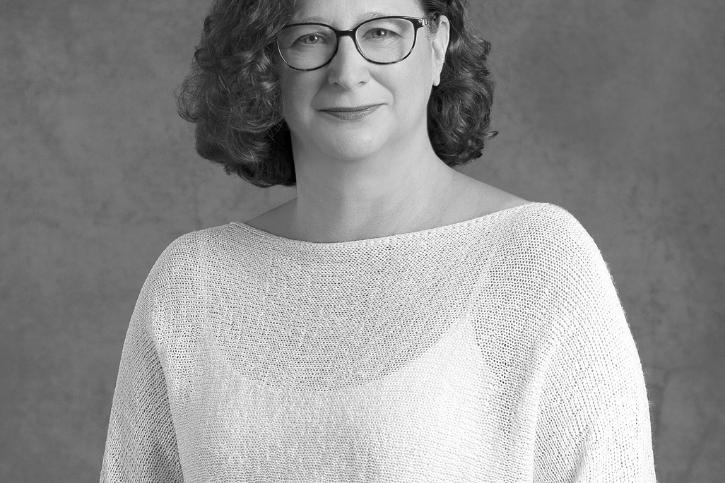 Black and white portrait of Rachel Johnson, Wimberly Interiors, smiling against a grey backdrop.