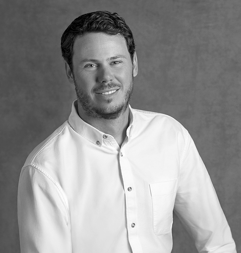 Black and white portrait of Rob Sykes, WATG, smiling against a grey backdrop.