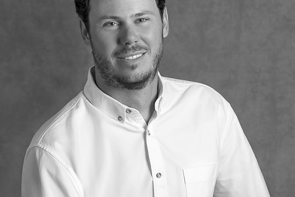 Black and white portrait of Rob Sykes, WATG, smiling against a grey backdrop.