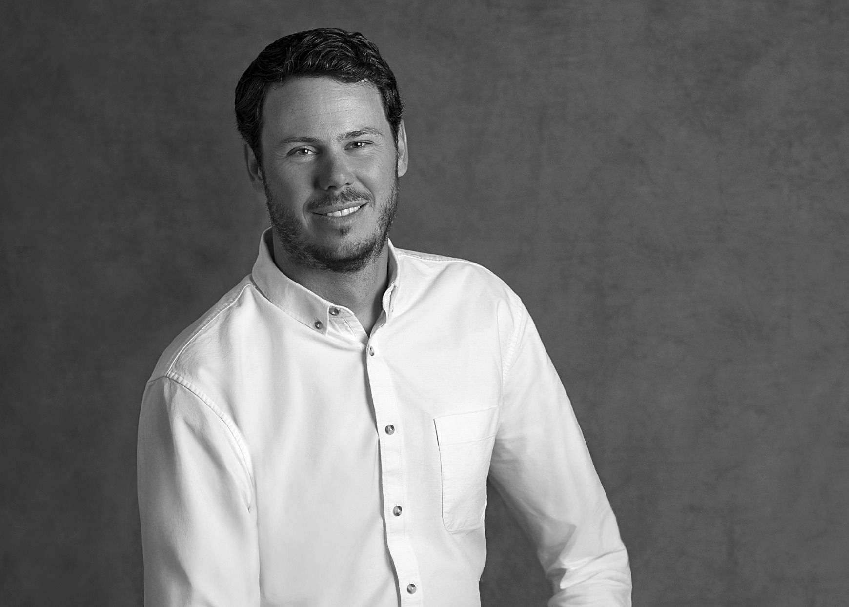 Black and white portrait of Rob Sykes, WATG, smiling against a grey backdrop.
