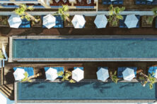 An aerial view of a pool with two lanes and two rows of white umbrellas