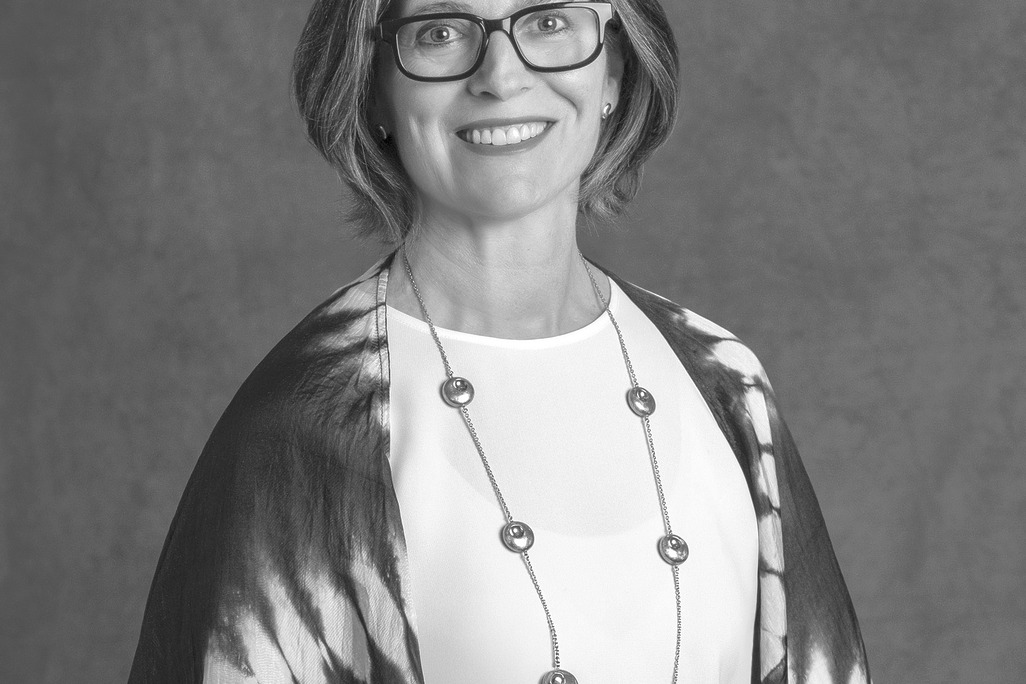 Black and white portrait of Chiara Calufetti-Lim, WATG, smiling against a grey backdrop.