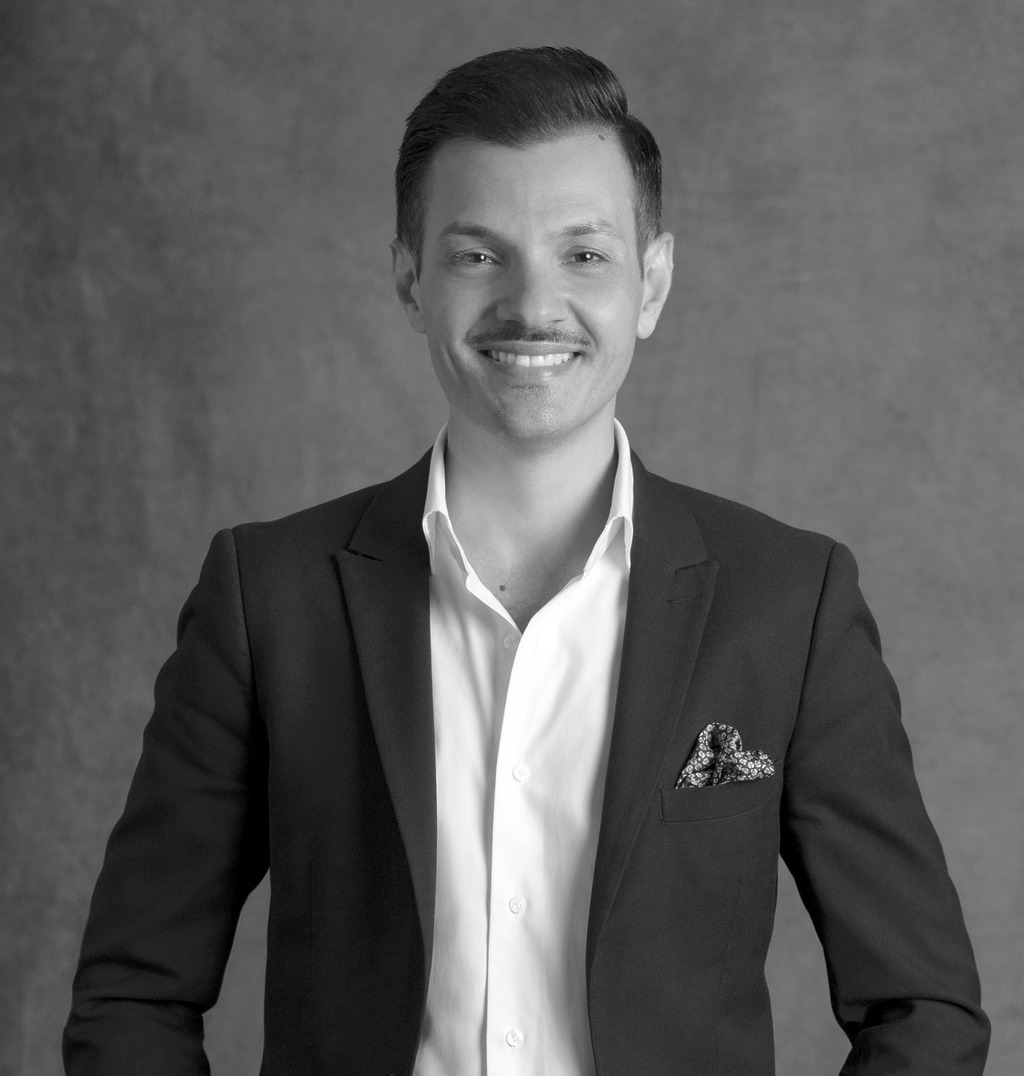 Black and White portrait of Damien Follone, Wimberly Interiors, smiling against a grey backdrop.