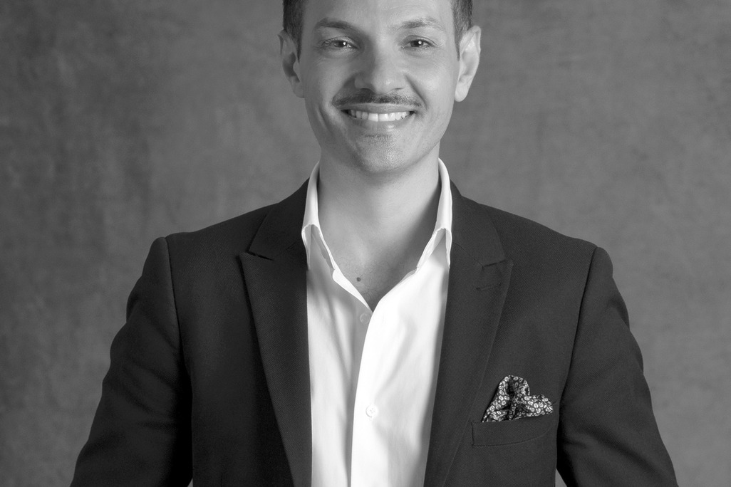 Black and White portrait of Damien Follone, Wimberly Interiors, smiling against a grey backdrop.