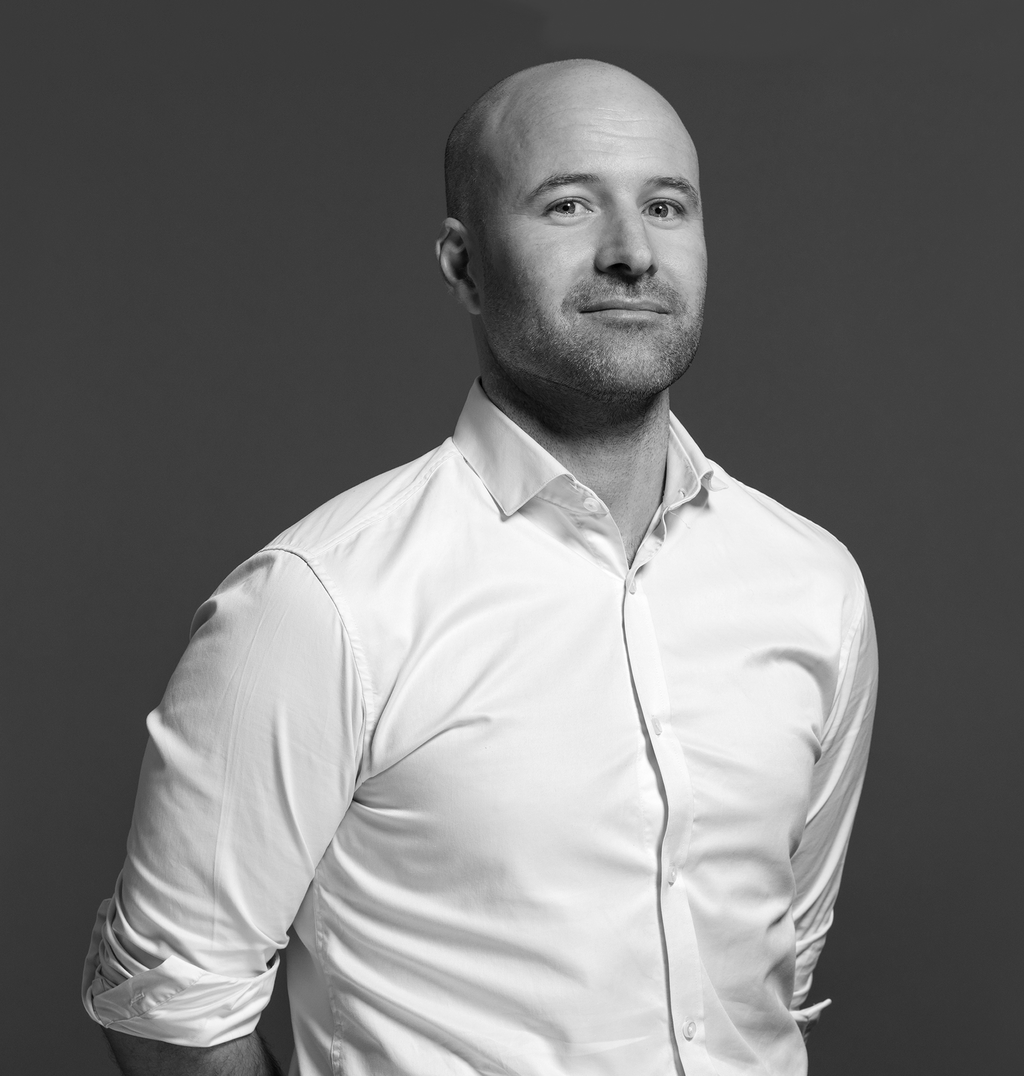 Black and white portrait of Dan Hinch, WATG, smiling against a grey backdrop.