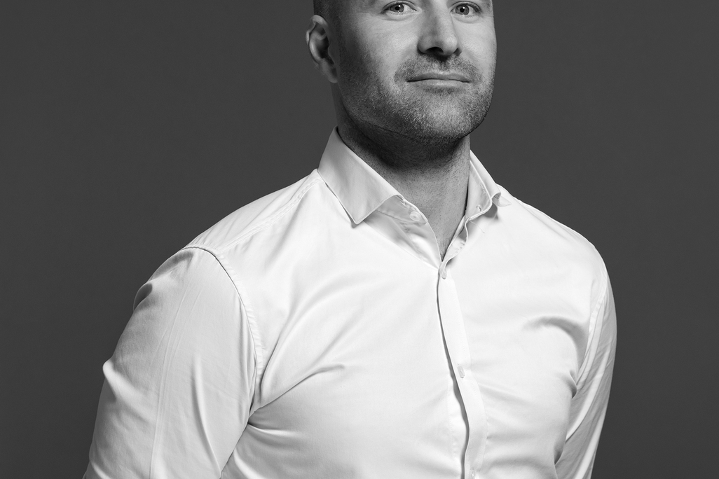 Black and white portrait of Dan Hinch, WATG, smiling against a grey backdrop.