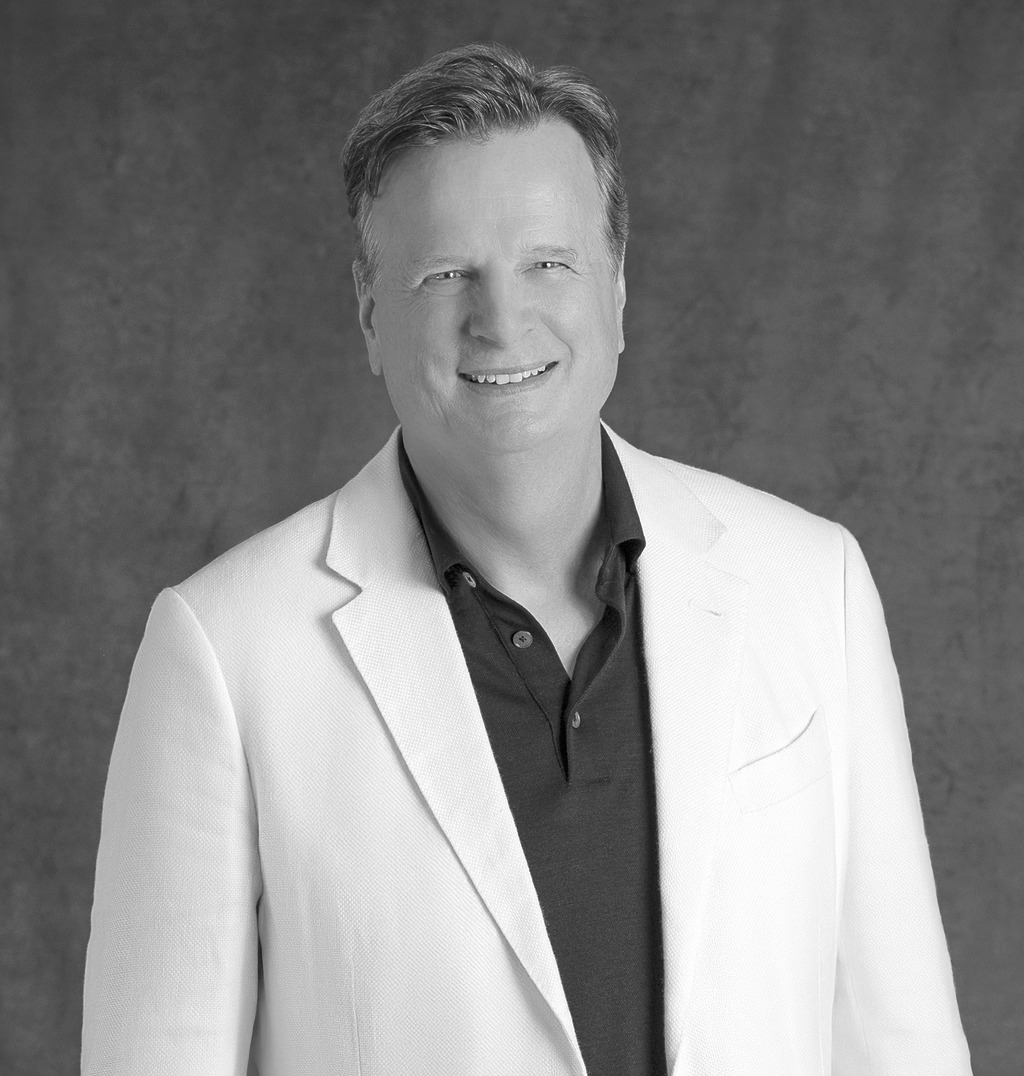 Black-and-white portrait of David Moore, CEO of WATG, smiling against a grey backdrop.
