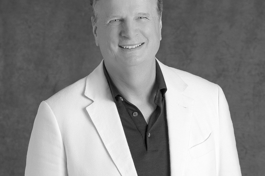 Black-and-white portrait of David Moore, CEO of WATG, smiling against a grey backdrop.