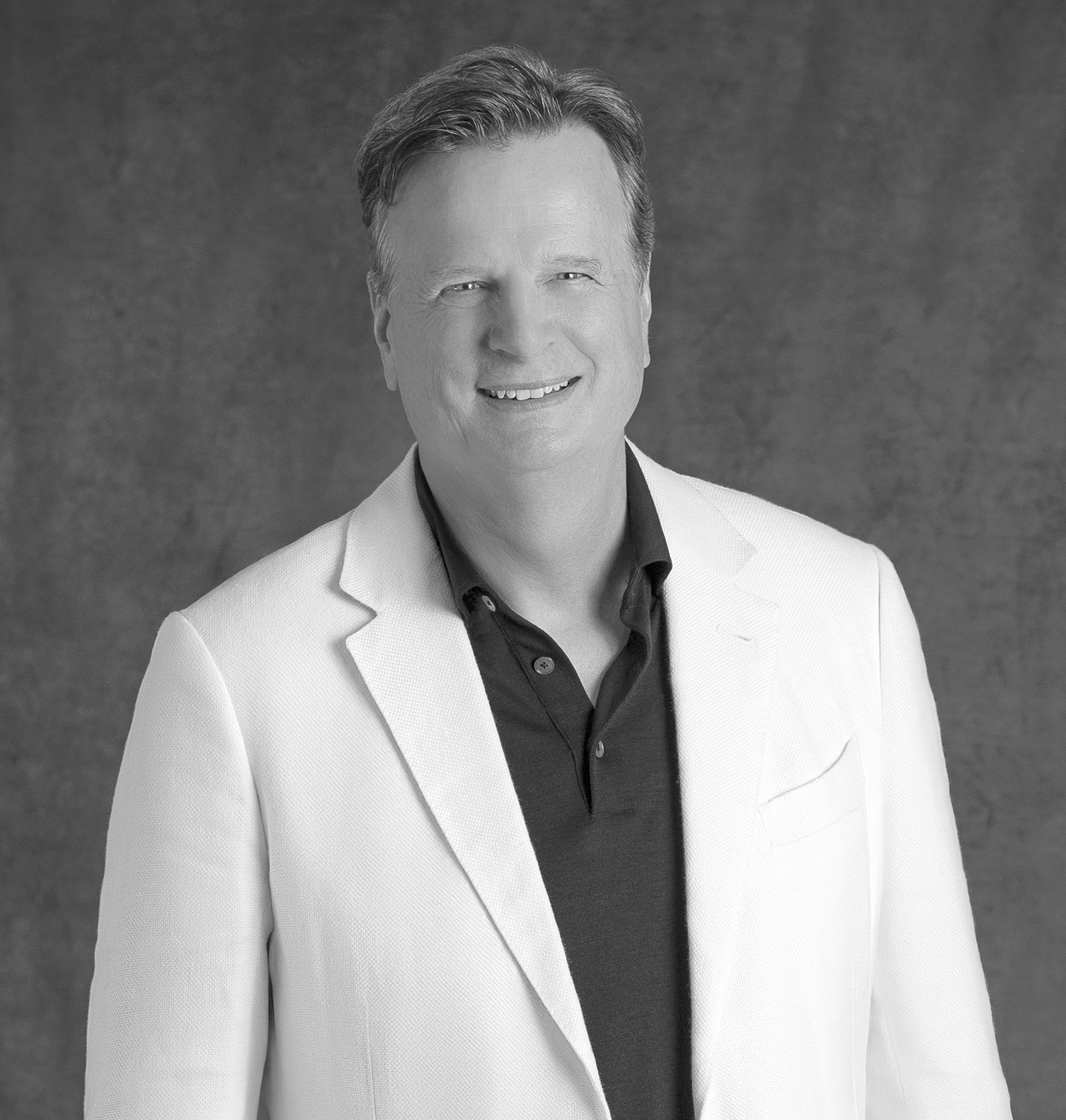 Black-and-white portrait of David Moore, CEO of WATG, smiling against a grey backdrop.