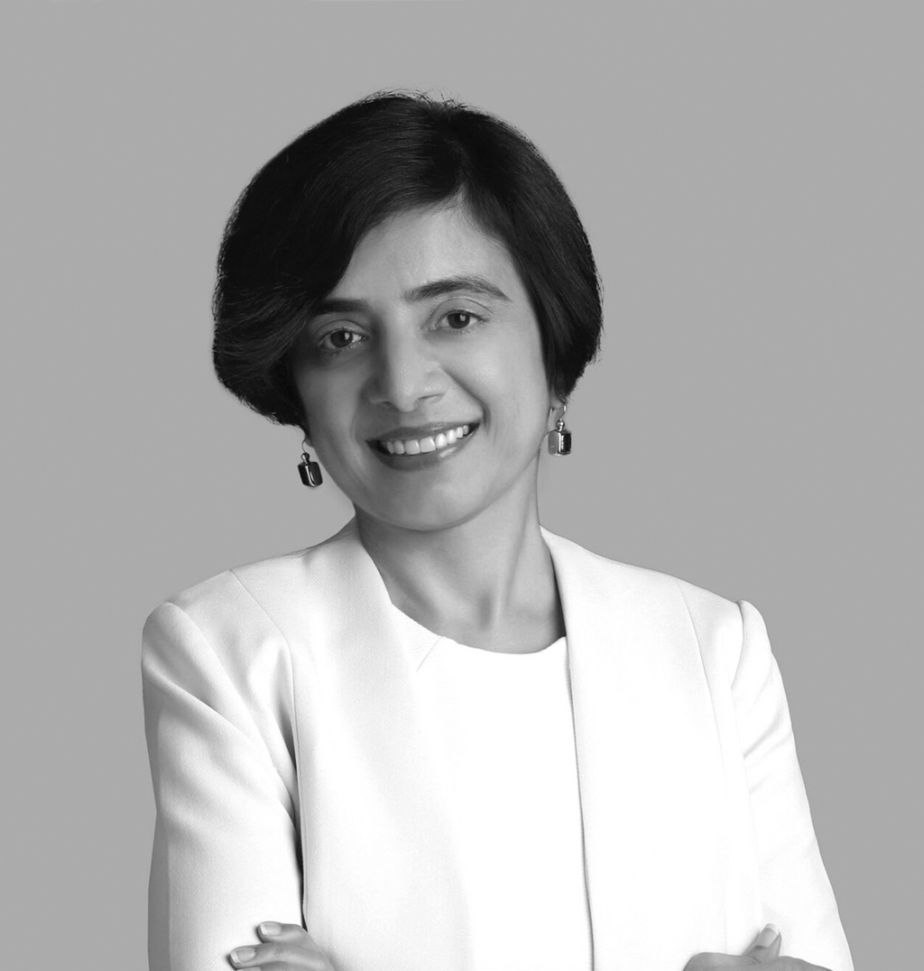 Black and white portrait of Deepu Mahboobani, Wimberly Interiors, smiling against a grey backdrop.