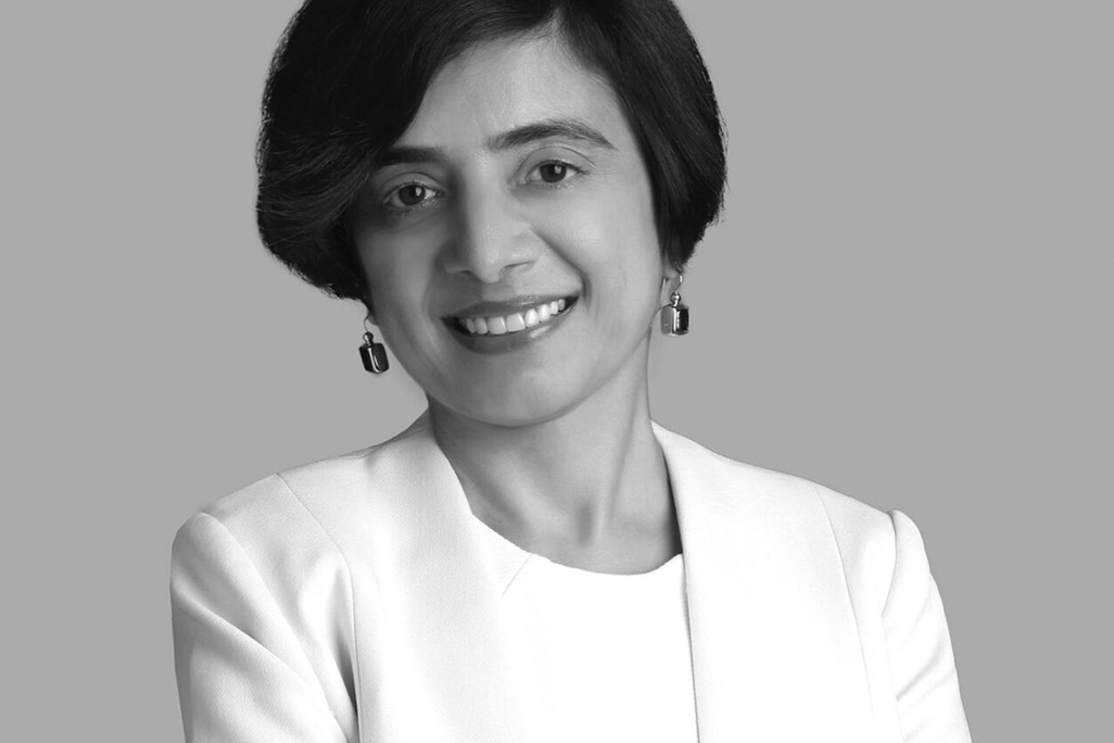 Black and white portrait of Deepu Mahboobani, Wimberly Interiors, smiling against a grey backdrop.
