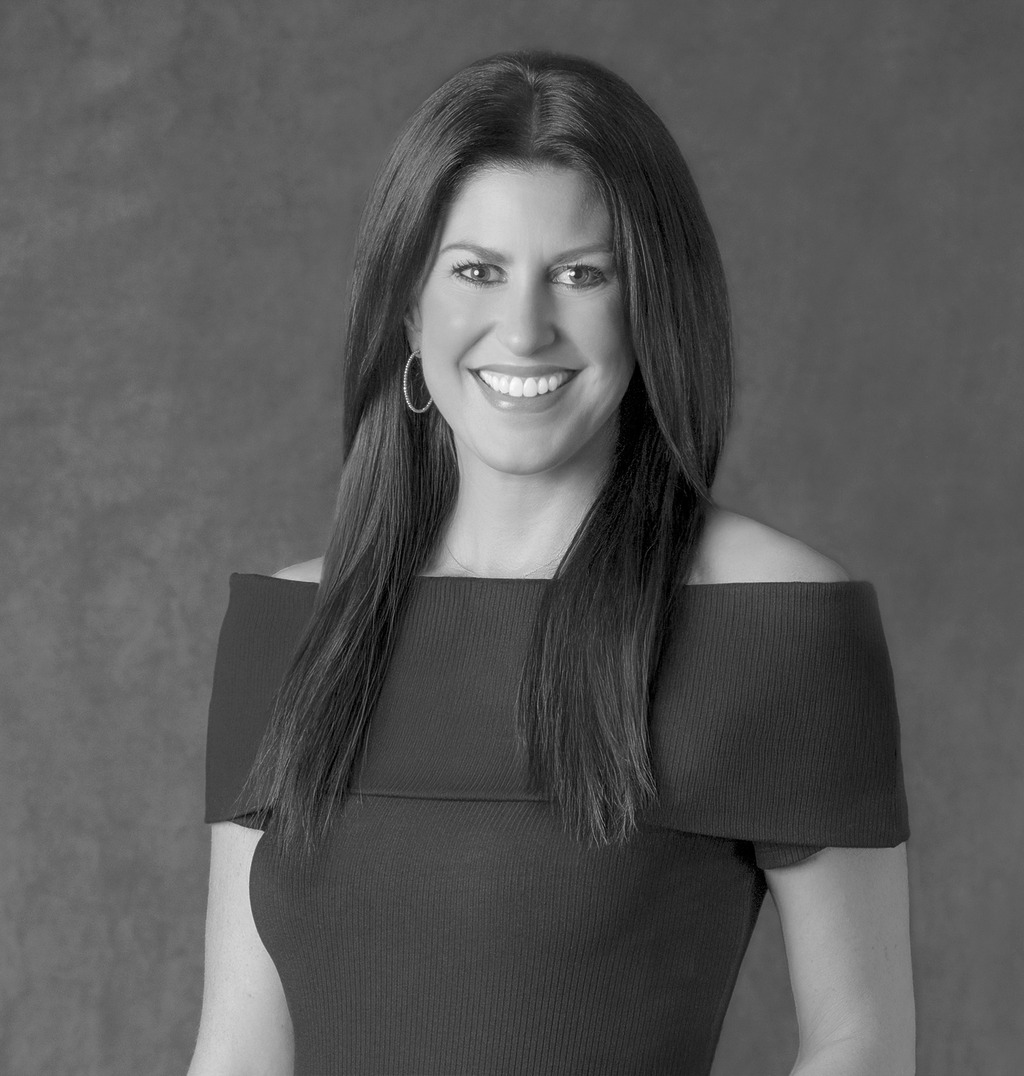 Black and white portrait of Erin Nichols Walker, Wimberly Interiors, smiling against a grey backdrop.
