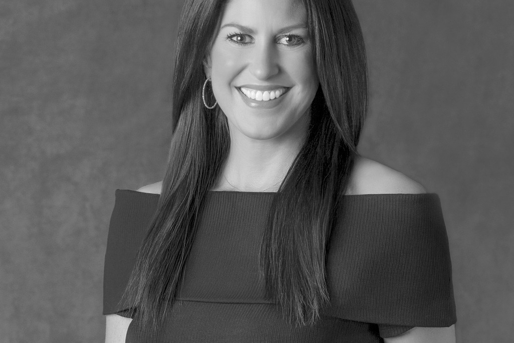 Black and white portrait of Erin Nichols Walker, Wimberly Interiors, smiling against a grey backdrop.