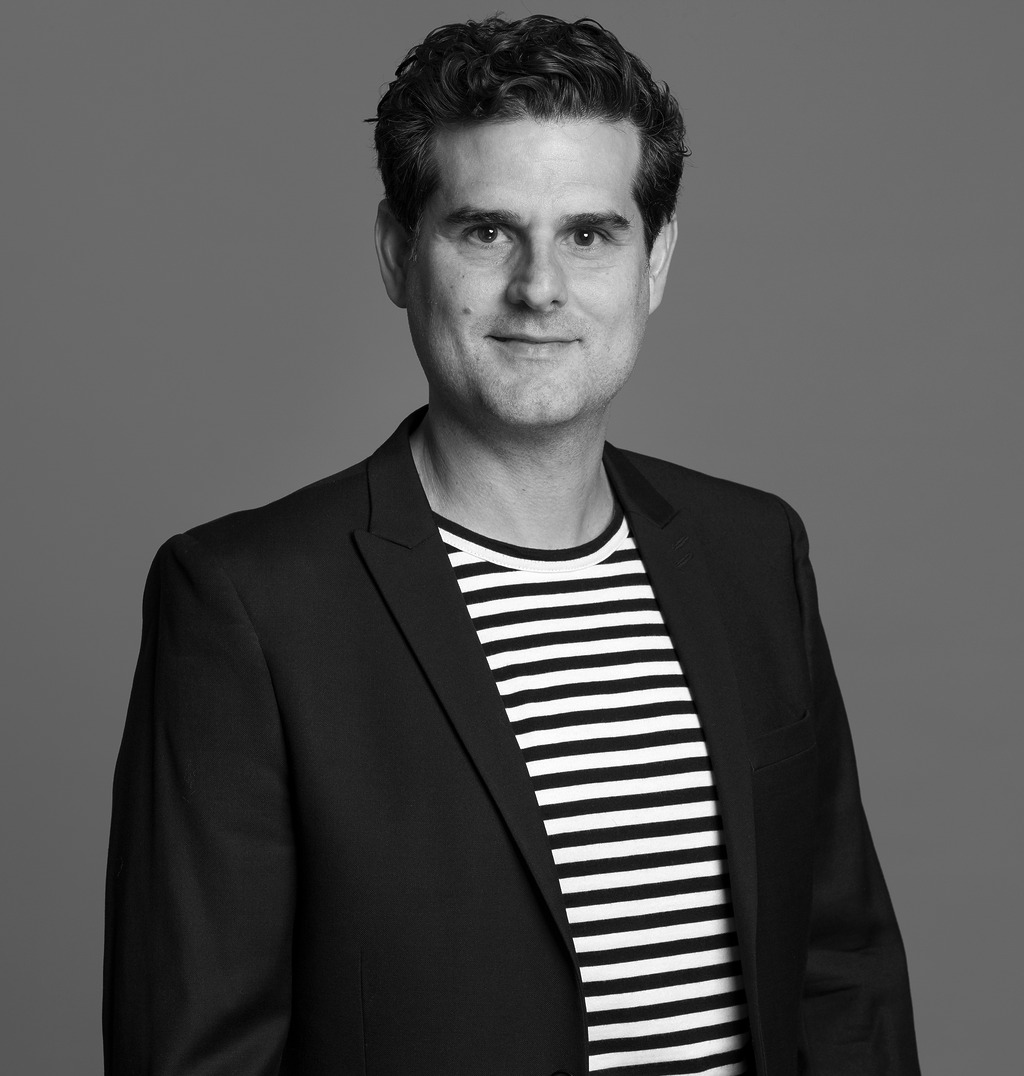 Black and white portrait of German Mendoza, Wimberly Interiors, smiling against a grey backdrop.