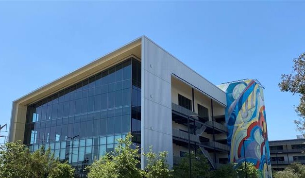 Tustin office building exterior with glass façade, colorful mural, and parking area in modern business park setting