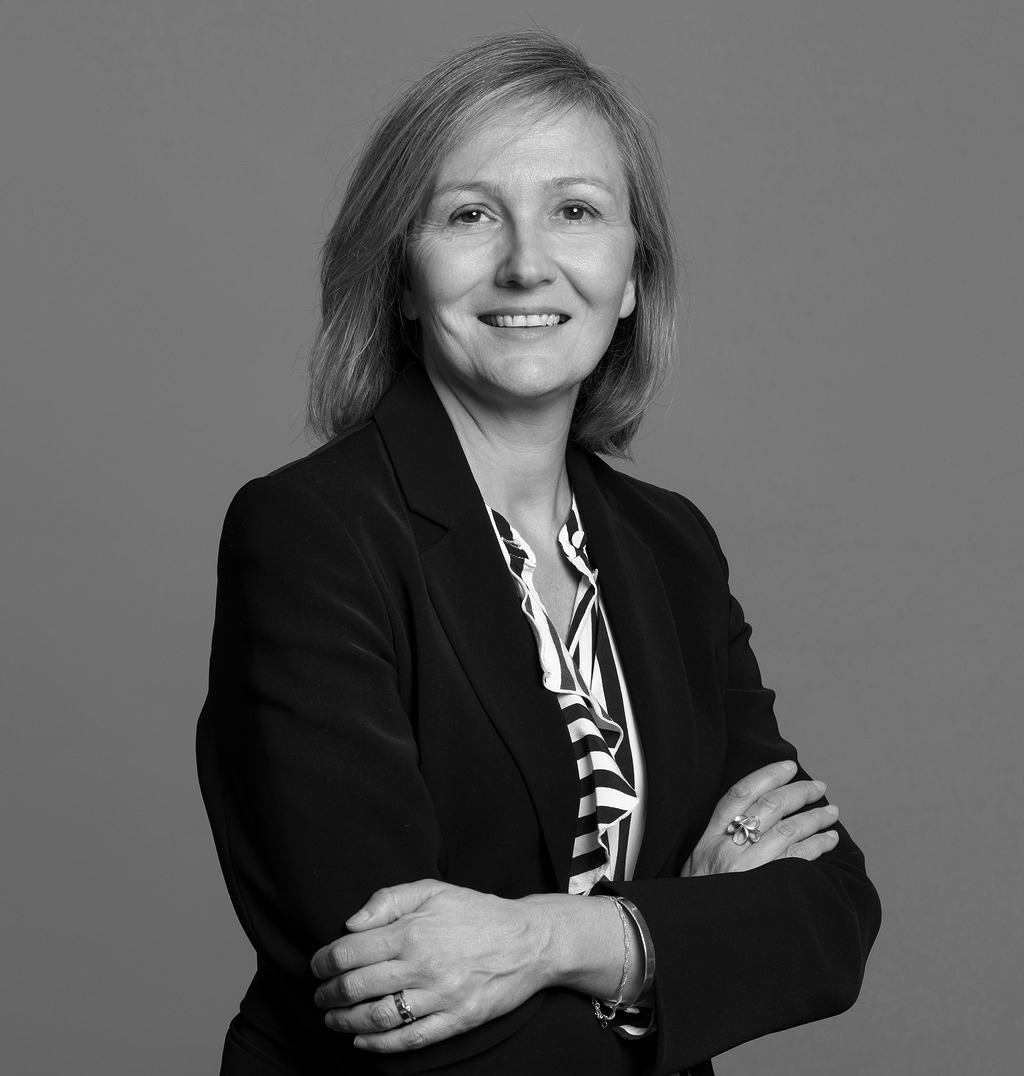 Black and white portrait of Eugenia Rolando, WATG, smiling against a grey backdrop.