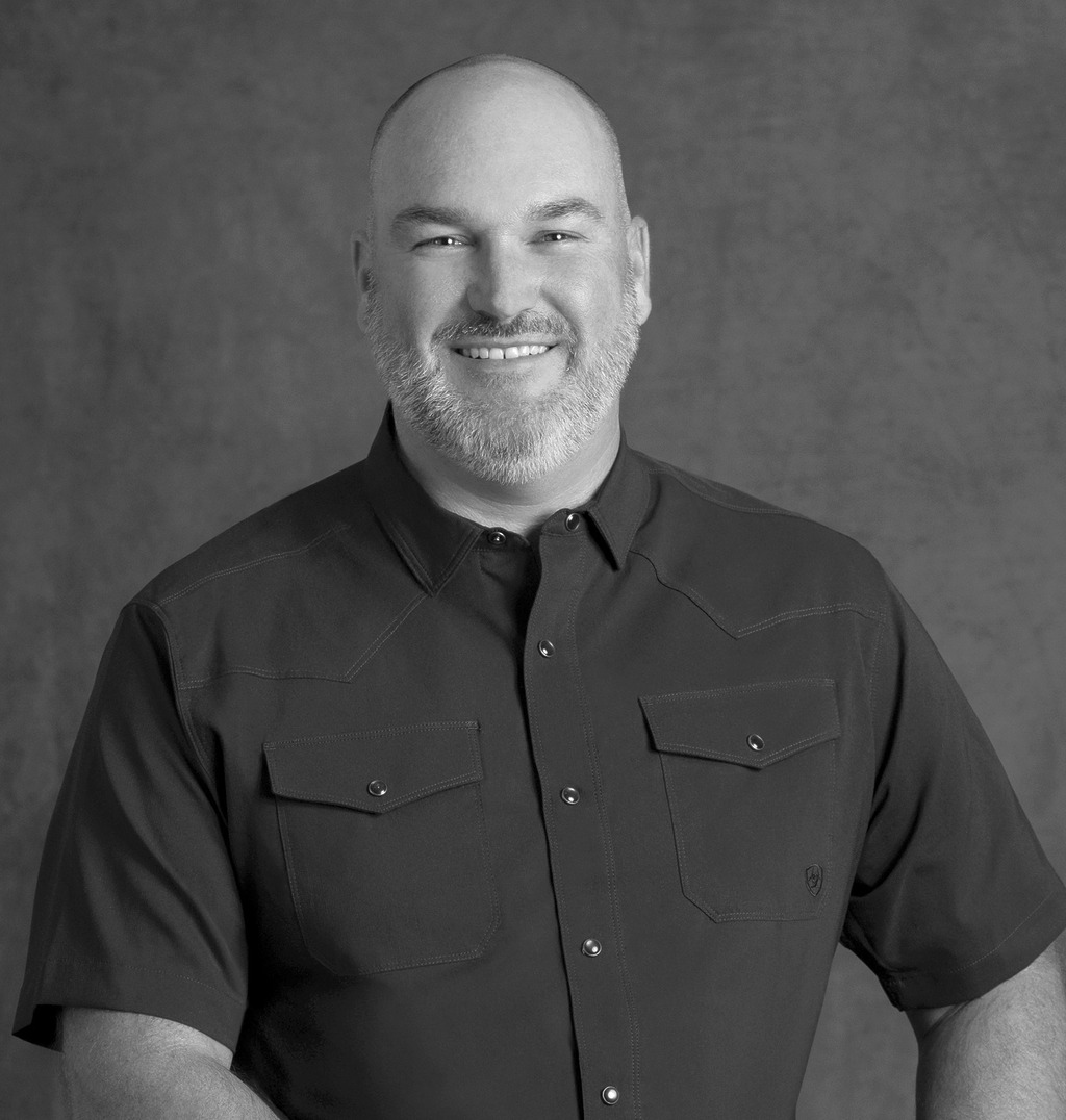 Black and white portrait of Marc Davies, WATG, smiling against a grey backdrop.