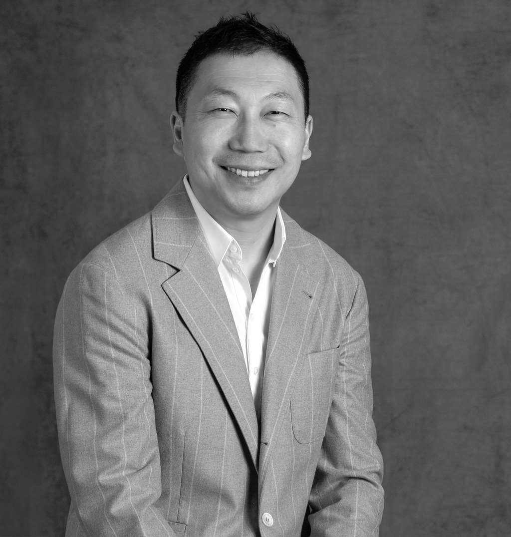 Black and white portrait of Liu Haoyang, Senior Director, Client Services, WATG, smiling against a grey backdrop.