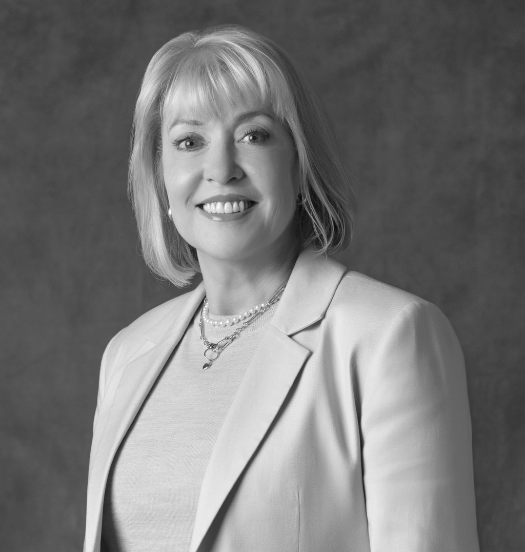 Black and white portrait of Kathy Chavez, Wimberly Interiors, smiling against a grey backdrop.