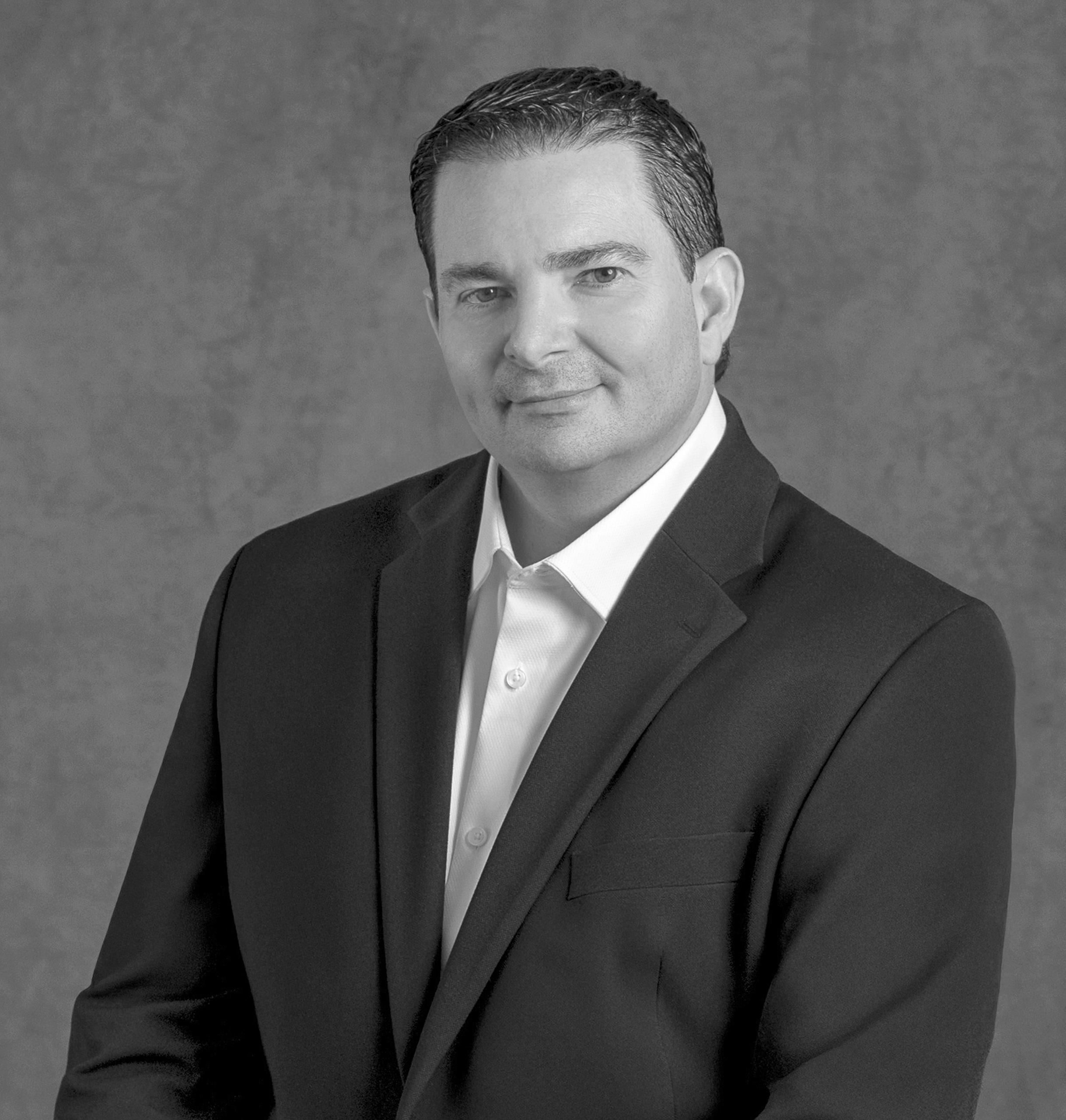 Black and white portrait of Richard Luis, WATG, smiling against a grey backdrop.