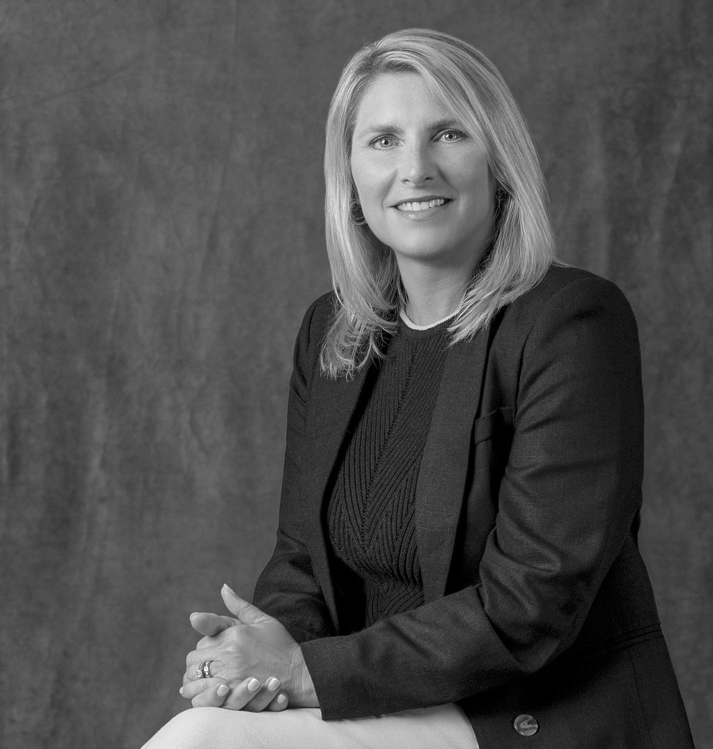 Black and white portrait of Kimberly McCarron, WATG, smiling against a grey backdrop.