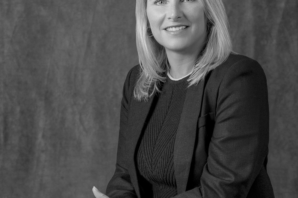 Black and white portrait of Kimberly McCarron, WATG, smiling against a grey backdrop.