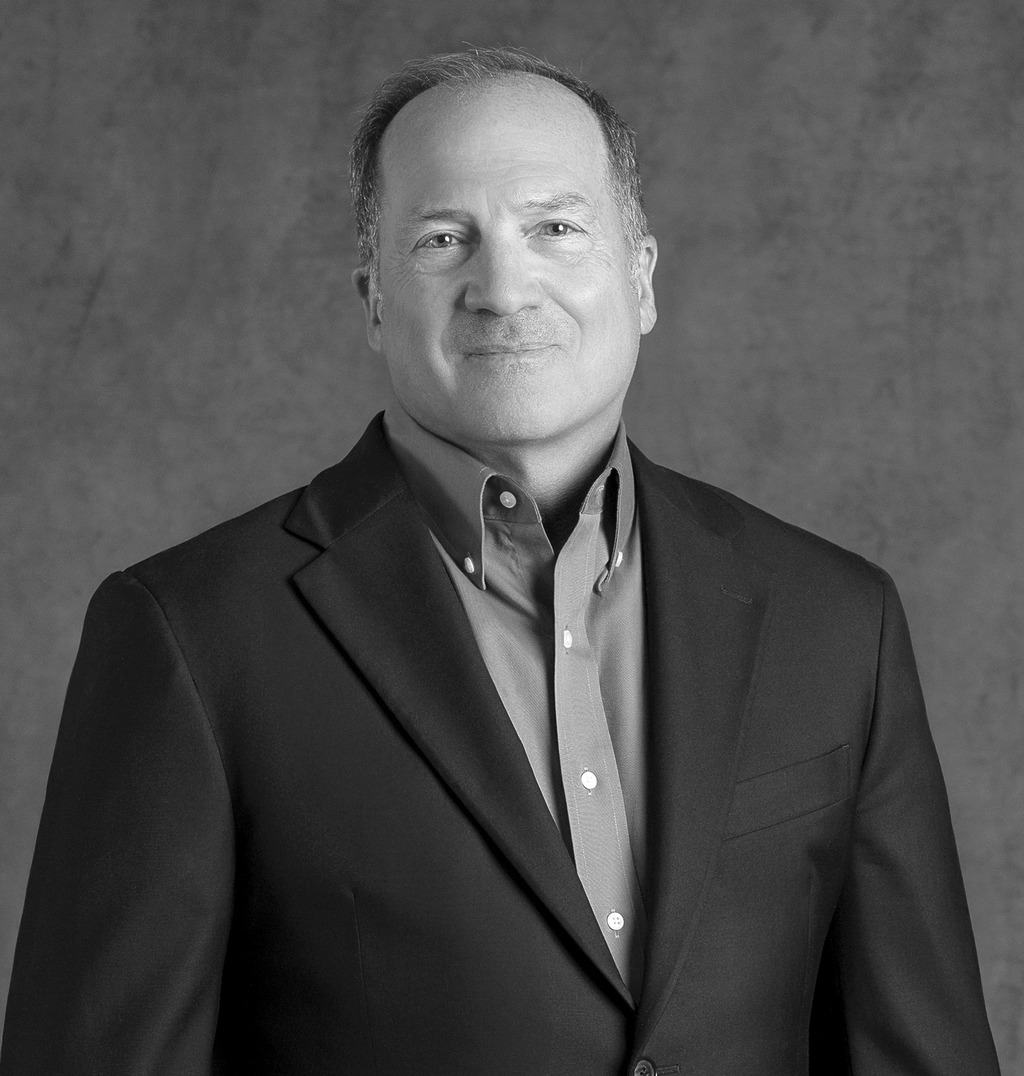 Black and white portrait of William Salerno, WATG, smiling against a grey backdrop.