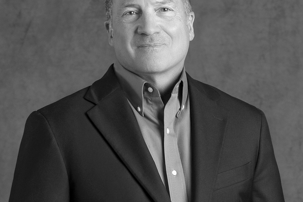 Black and white portrait of William Salerno, WATG, smiling against a grey backdrop.